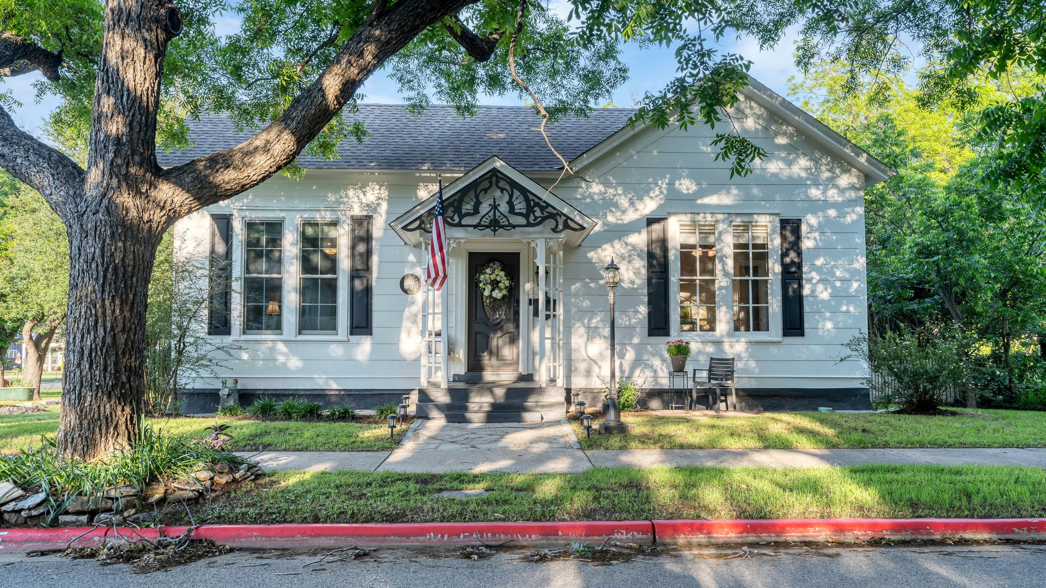 Front exterior view of 1305 S College St in Georgetown Texas with mature trees and historic character
